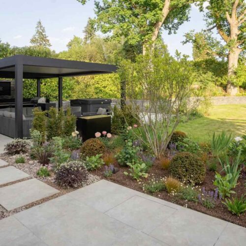 Contemporary Hertfordshire Garden with pale grey porcelain paving, steel pergola, sociable outdoor lounge and dining areas and steel pergola with hot tub