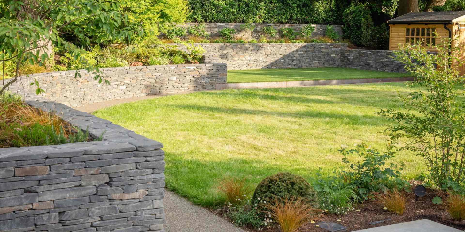 Large country garden with slate clad retaining walls and colourful planting