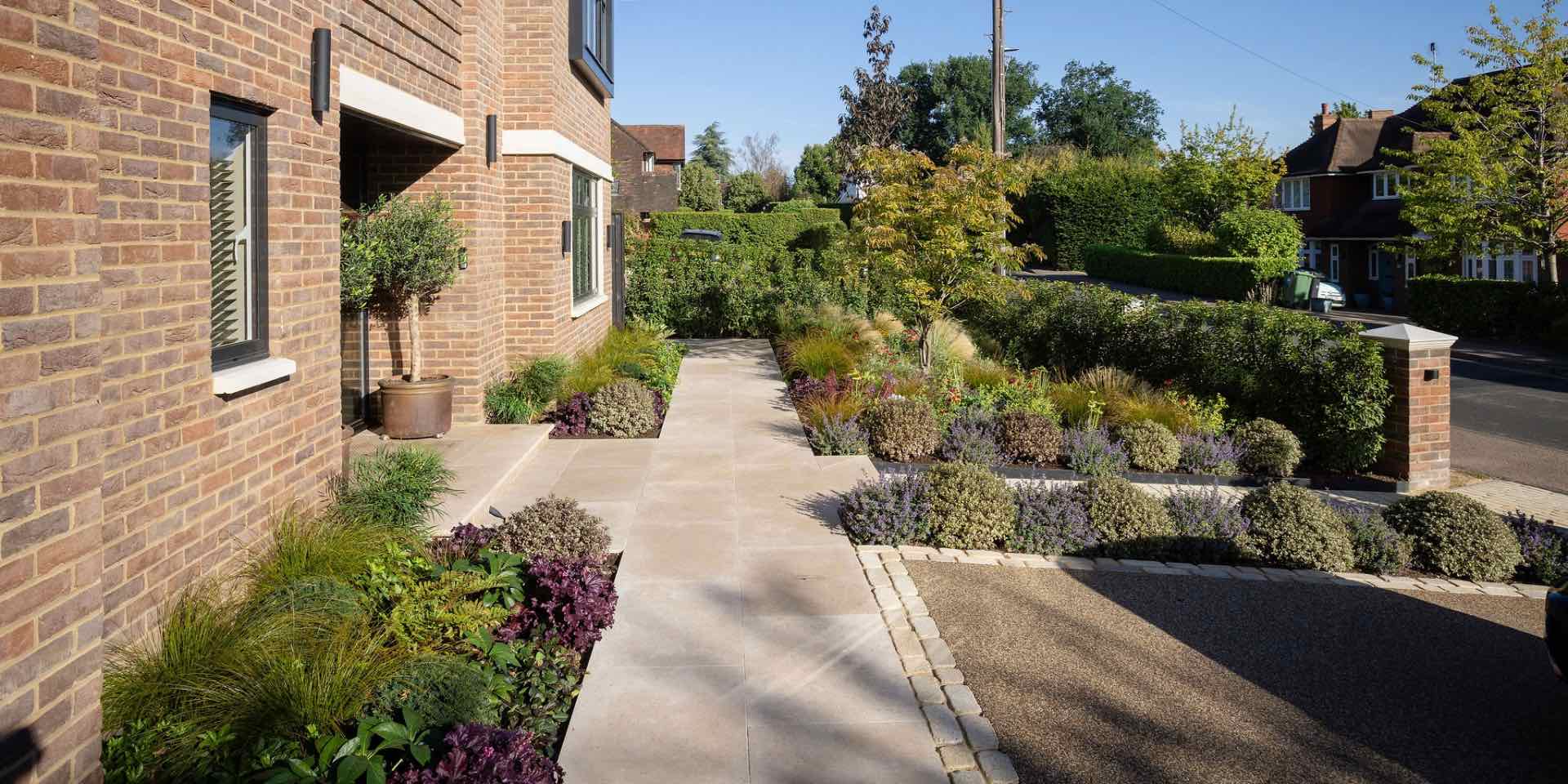 Limestone paving to luxury home entrance with colourful low maintenance planting and yellow granite sett edging
