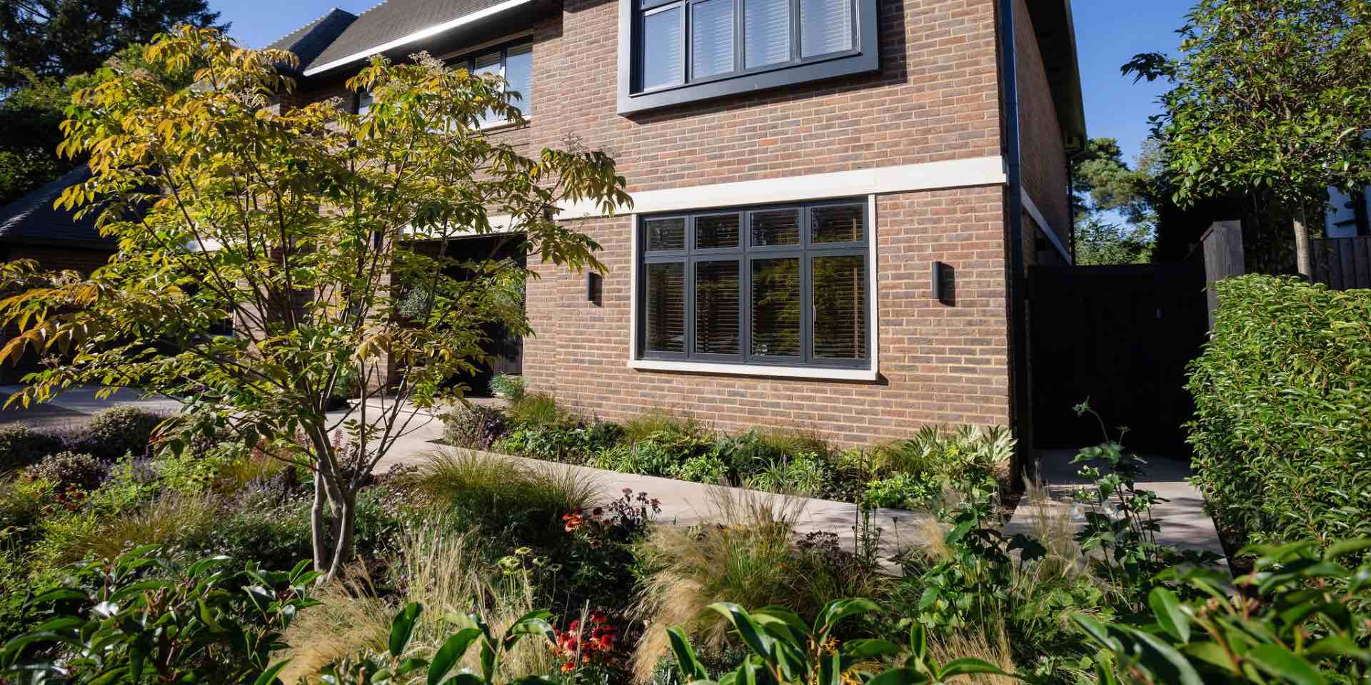 Front garden for a new build home with limestone with colourful planting for sunshine and small garden tree